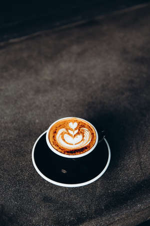 White cup of tasty cappuccino with latte art on white marble background in cafe, Loft interior,の写真素材