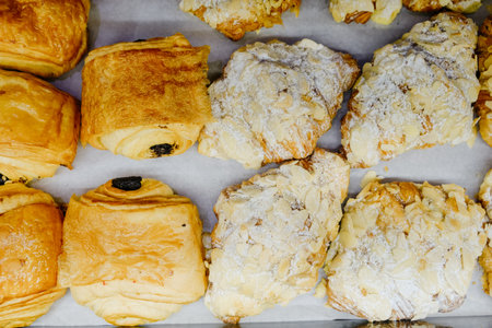 Various pastries with almonds and powdered sugar on display.の写真素材