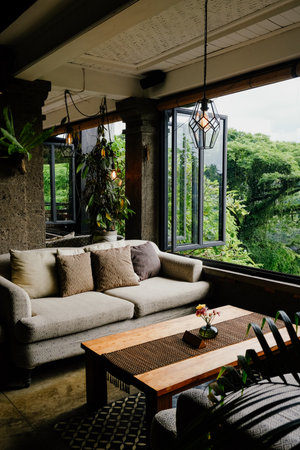 Comfortable lounge setting with sofa and wooden table overlooking greeneryの写真素材