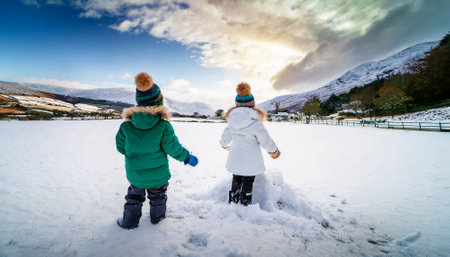 Children playing with snow in a snowy field in winter, back viewの素材
