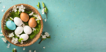 Easter eggs in a basket with spring flowers on turquoise backgroundの素材
