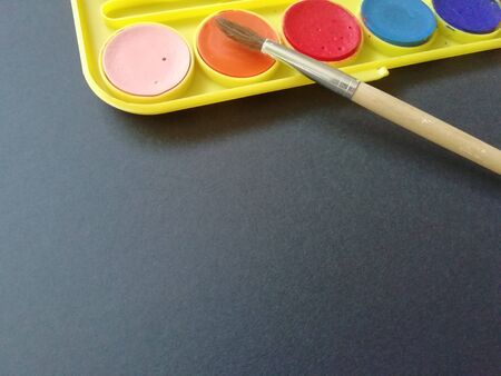 Multicolored paints with a brush on a black background with a place for textの写真素材