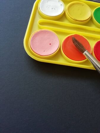 Multicolored paints with a brush on a black background with a place for textの写真素材