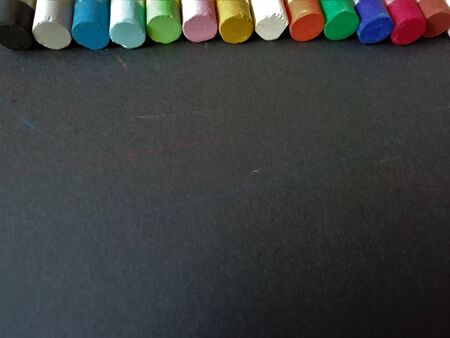 Multi-colored chalk on a black background with a place for textの写真素材