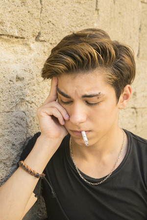 the guy is a teenager with a cigarette outdoorsの写真素材