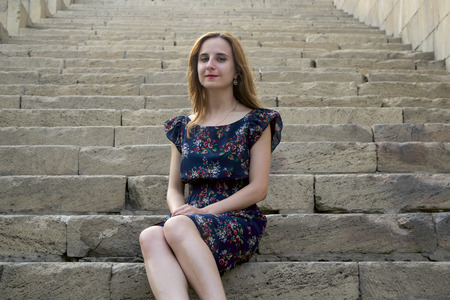 young long-haired blonde girl on the stairsの写真素材