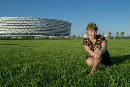 fat blonde woman sitting on green grass in summerのeditorial素材