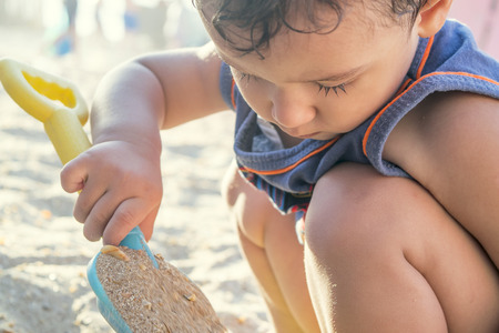 boy on the beach playing with sandの写真素材