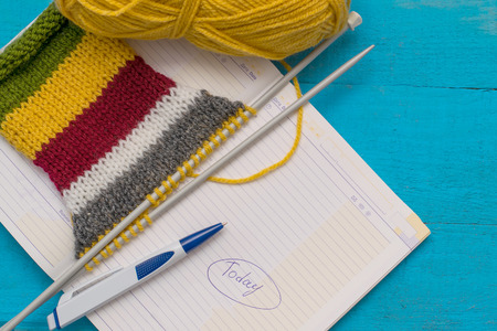 knitting with notebook on blue wooden table