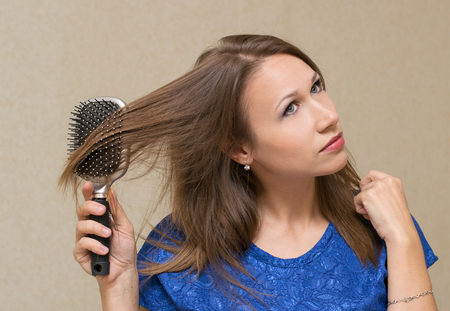 woman combing long brown hair comb , indoorsの写真素材
