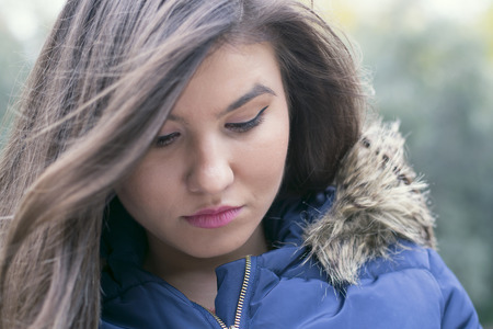 sad brunette girl looking down outdoorsの写真素材