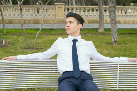 fashionable young man sits on a bench in the Parkの写真素材