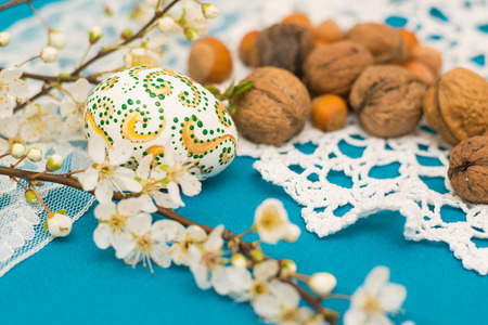 the painted egg, walnuts and blossoming branch on a napkinの写真素材