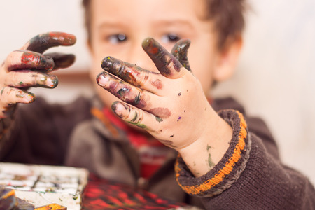 boy draws with hands soiled in a paintの写真素材