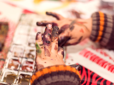 the boy paints with watercolors on paper, dirty handsの写真素材