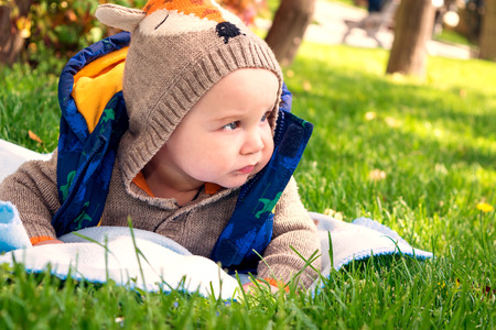 little baby is 6 months lying on the grass in the spring