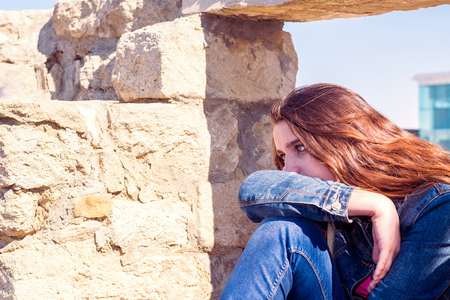 young woman in depression near the stone wallの写真素材