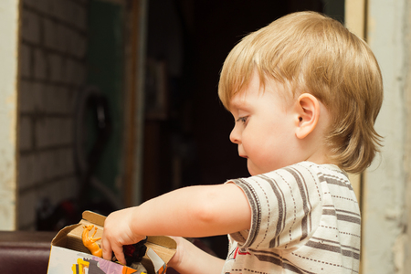 blonde boy pulls toy out of the boxの写真素材
