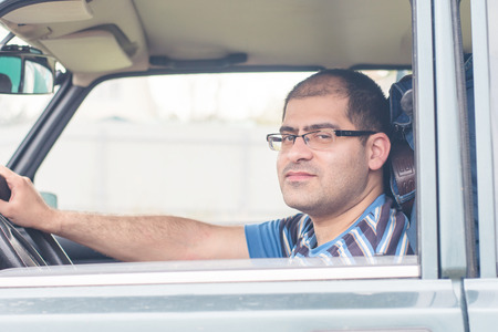 male driver sitting in the car and smiling