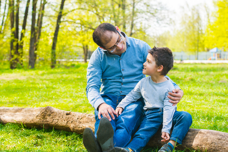 dad and son sitting on a log in the meadowの写真素材