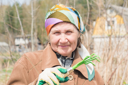 elderly woman with a garden rake in handの写真素材