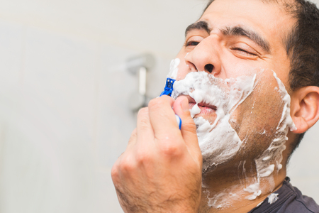 middle-aged man shaves his face in the bathroomの写真素材