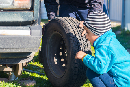 father and son change a tire on the carの写真素材