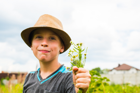 teen boy with daisies in hand in summerの写真素材