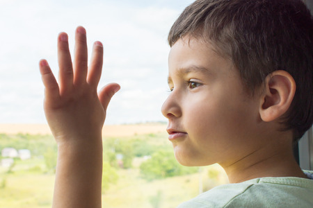 brunette boy looks at the window of the train with interestの写真素材