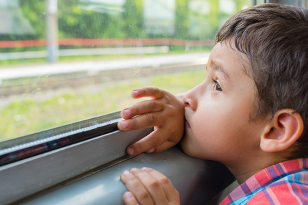 sad boy rides a train and looks out the window