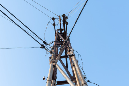 Pole with high-tension wires on the sky background
