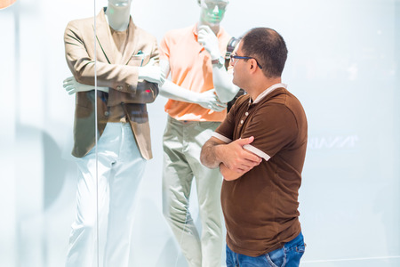 Young man stands near the window of a clothing store