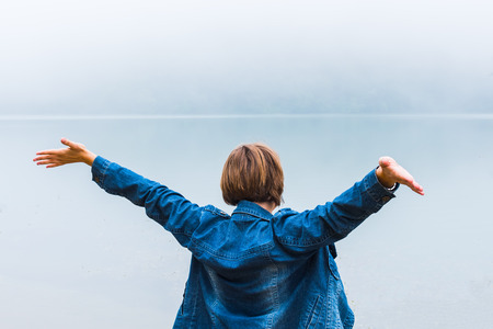 young woman with hands up on background of lake