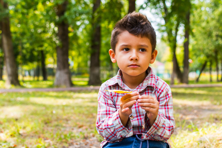 boy sitting on a log in the Park with a yellow leafの写真素材