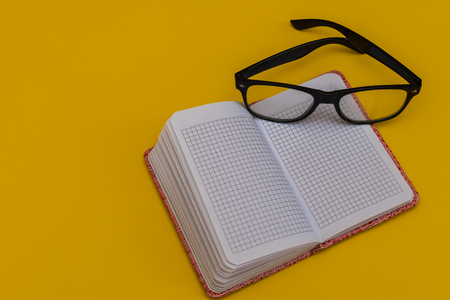 Notepad, glasses and clock on yellow backgroundの写真素材