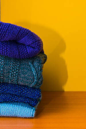 stack of knitted clothes on yellow backgroundの写真素材