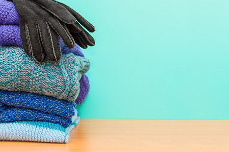 stacked knitted clothes and gloves on blue backgroundの写真素材