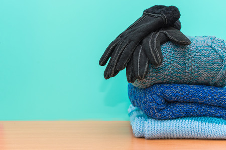 stacked knitted clothes and gloves on blue backgroundの写真素材