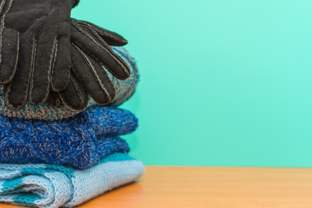 stacked knitted clothes and gloves on blue backgroundの写真素材