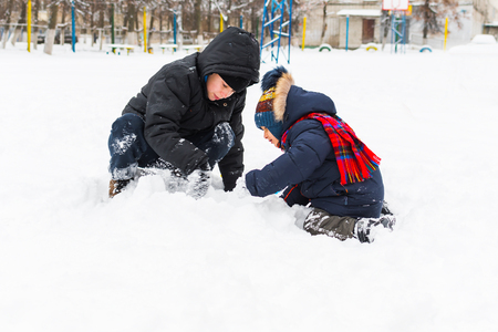two boys play in winter in the snowの写真素材
