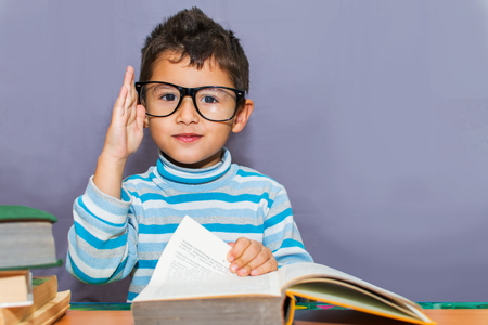 boy preschooler with glasses for books on the desktopの写真素材