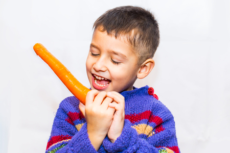 brown-eyed boy with carrots on a light backgroundの写真素材