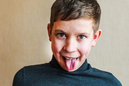 teen boy shows tongue indoorsの写真素材