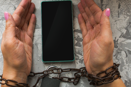 hands tied with a chain, smartphone. the concept of disability, prohibition.の写真素材
