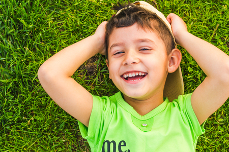 cheerful smiling boy lying on the grass in the summerの写真素材
