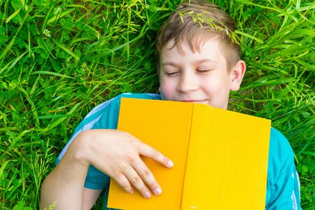teenage boy fell asleep with a book on the grass