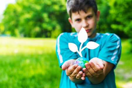 teen boy holding a globe with a plantの写真素材