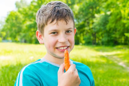 teen boy with a carrot in a forestの写真素材
