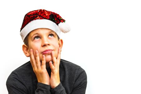 pensive boy in Santa hat on white isolated backgroundの写真素材