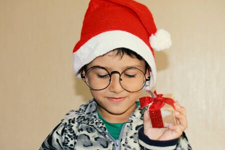 boy with glasses and Santa hat holding a small giftの写真素材